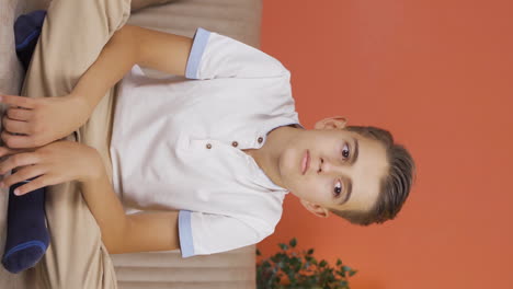 Vertical-video-of-Boy-at-home-looking-at-camera-with-a-calm-expression.